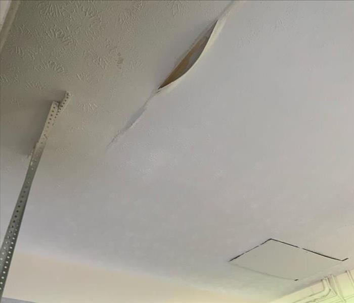 A garage ceiling has stains and damage from water.
