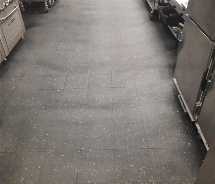 A commercial kitchen floor is dirty.