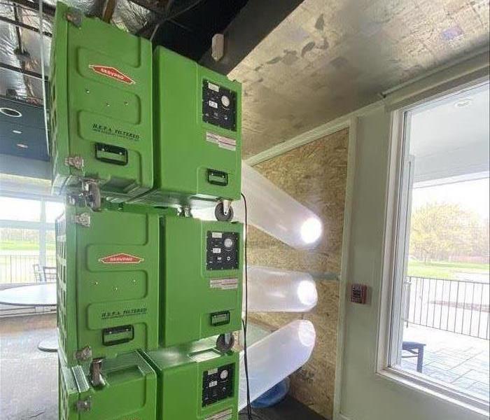 SERVPRO colored Air Scrubbers sit in a room damaged by fire.