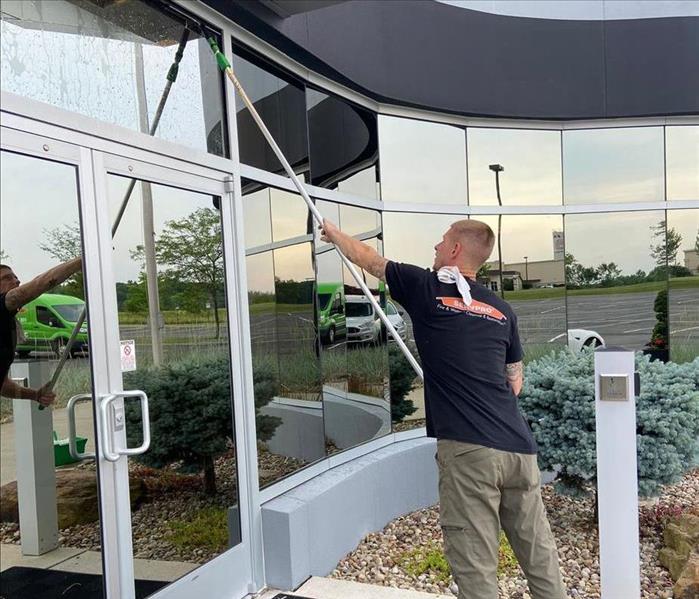 SERVPRO team member is cleaning exterior windows of a business.