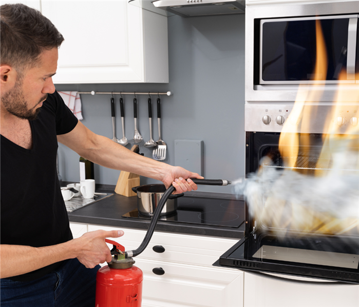 man using fire extinguisher on oven