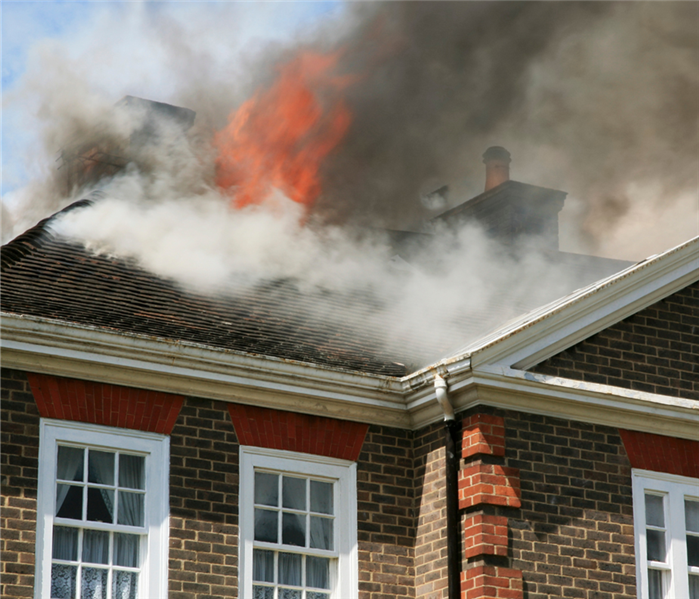 Brick house with flames coming out of roof.
