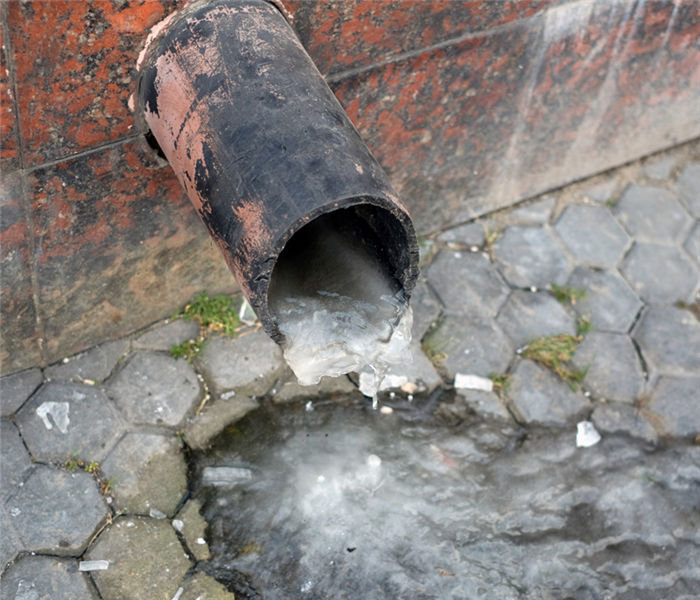 Picture shows a close up of a frozen outdoor pipe with ice coming out of it. 